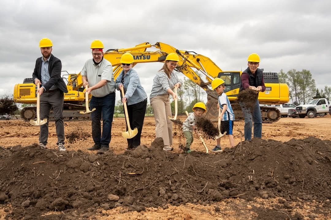A group in hard hats turning the first shovels of earth at an Alcove Development project groundbreaking